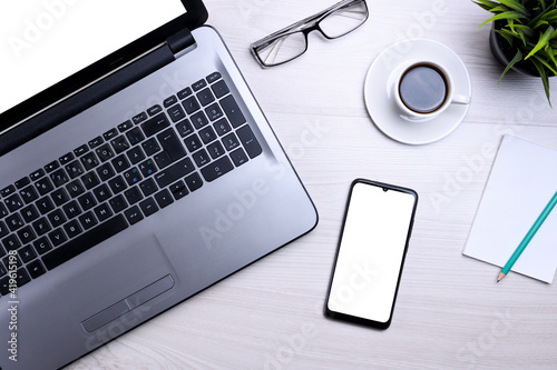 Smartphone, mobile phone with white screen on a gray laptop on the desktop. Mock up