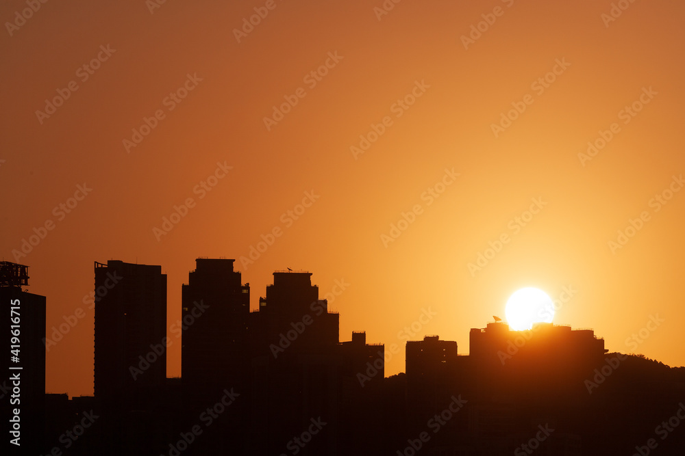 Sunrising behind a silhouette of a skyline