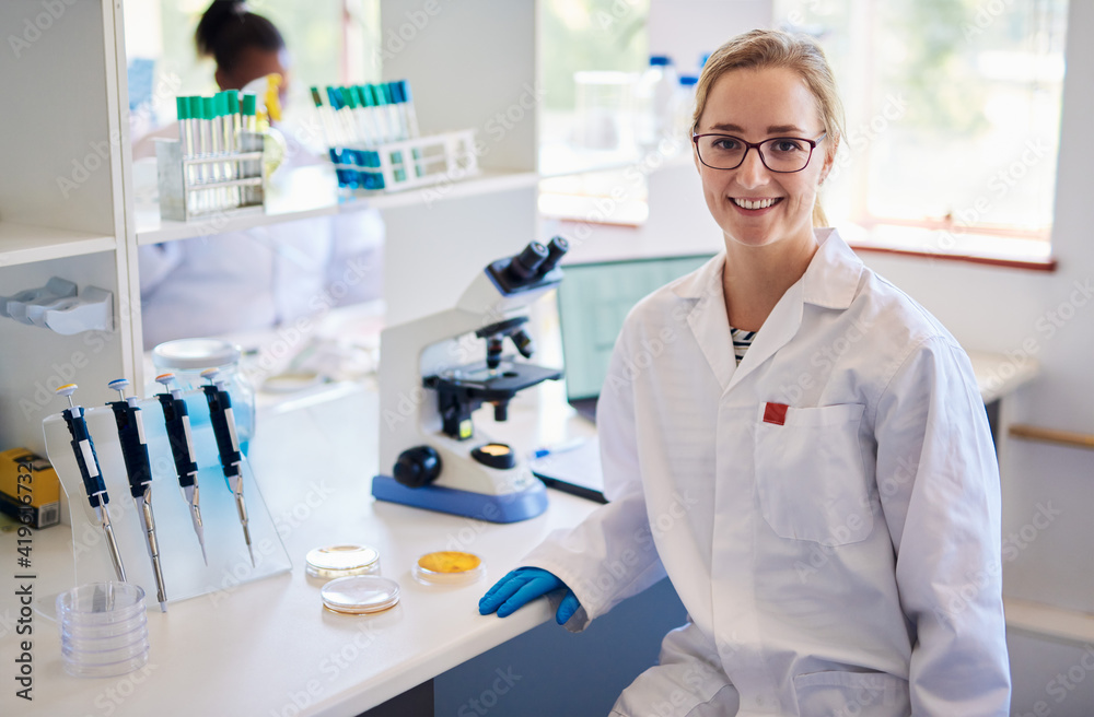 Fototapeta premium Smiling young female technician analyzing samples in a lab