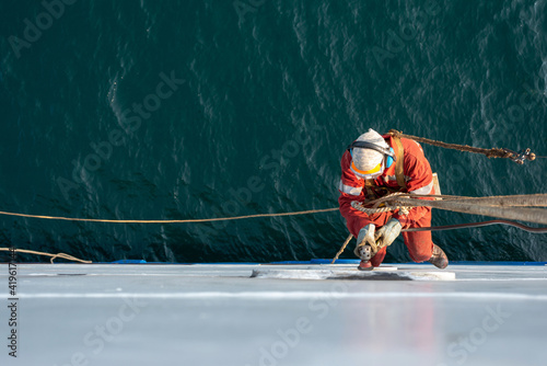 Fotografia, Obraz Seaman ship crew working aloft at height derusting and getting vessel ready for painting