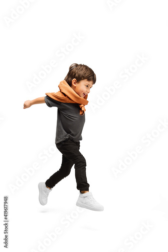 Jumping high. Happy, smiley little caucasian boy isolated on white studio background with copyspace for ad. Looks happy, cheerful. Childhood, education, human emotions, facial expression concept.