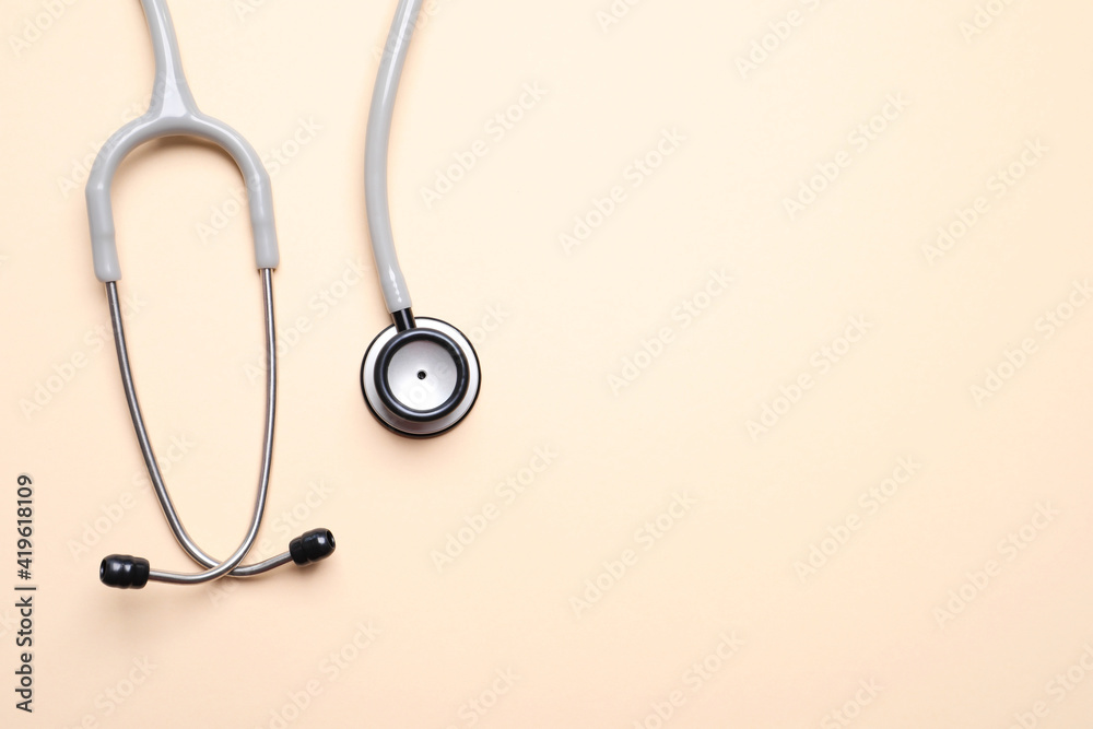 Stethoscope on beige background, top view. Space for text