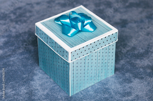 Kartonowy błękitny składany prezent położony na materiale.