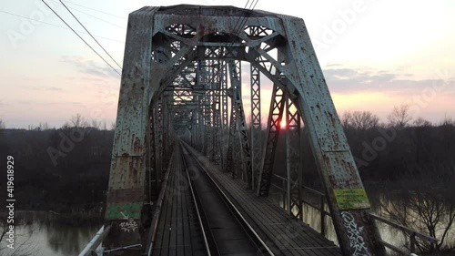 The railway bridge in Poland. It has an arched steel truss structure with a driving downhill, supported by five pillars.