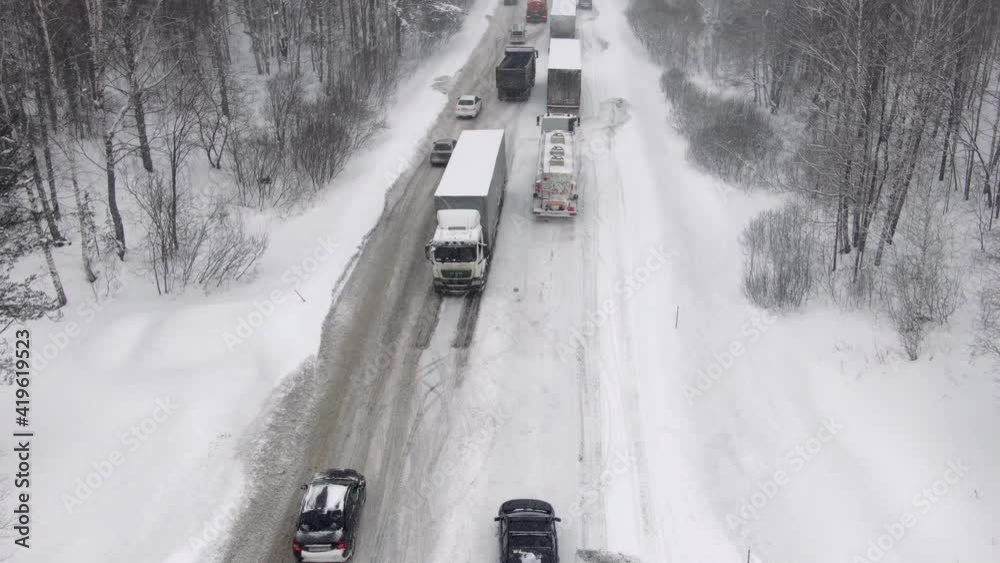 Trucks are stuck in traffic on a snow-covered highway. Thousands stranded on highway as major snowstorm and blizzard hits hard causing