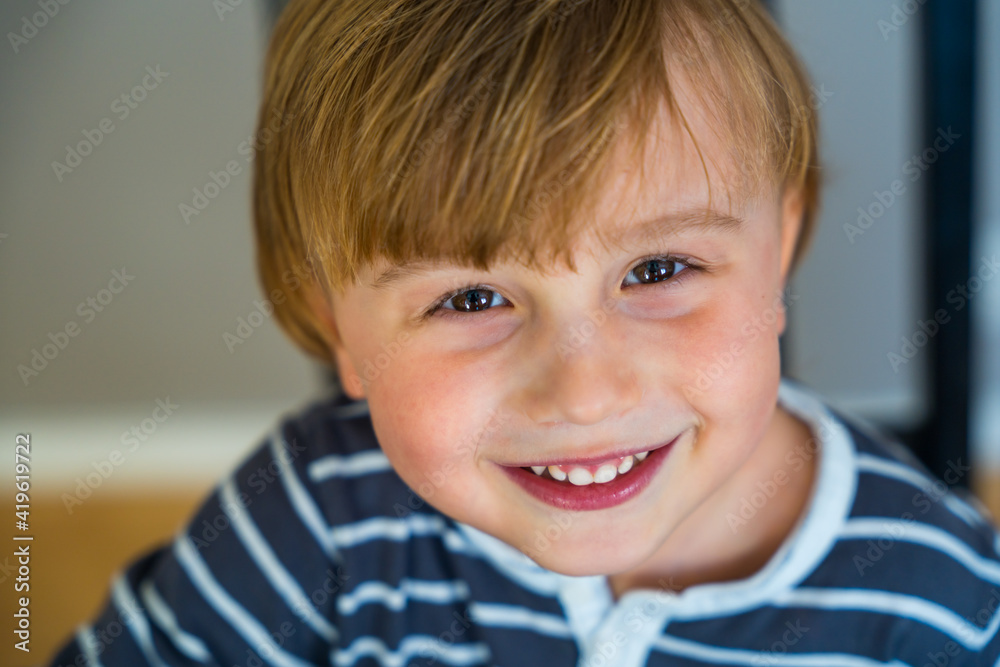 Close up portrait of a toddler boy of three years old indoor. Happy child wearing striped t shirt looking at the camera smiling with pleasure Close up portrait of a toddler boy of three years old indoor. Happy child wearing striped t shirt looking at the camera smiling with pleasure