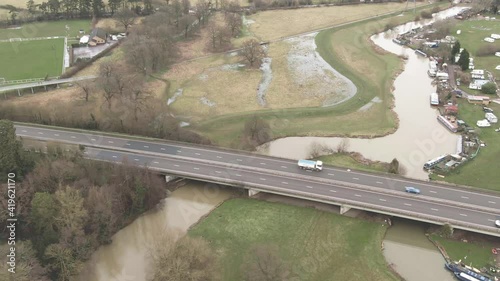 Aerial tracking along the A6 dual carriageway in Leicestershire, including River Soar, fields and sports pitch in background photo