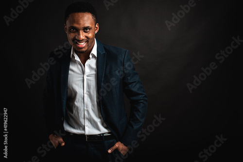 portrait of attractive, beautiful, serious and stylish professional African American businesswoman in dark suit and white shirt isolated on dark background. Low key. Selective focus 