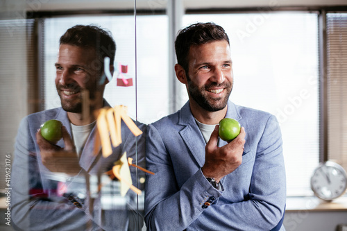 Businessman in conference room eating apple. Young businessman having healthy snack. photo