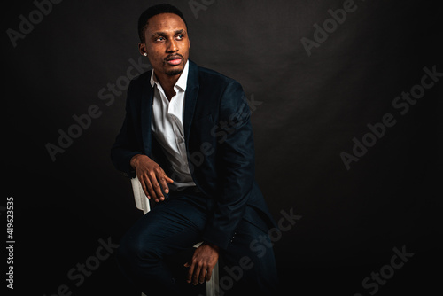 portrait of attractive, beautiful, serious and stylish professional African American businesswoman in dark suit and white shirt isolated on dark background. Low key. Selective focus 