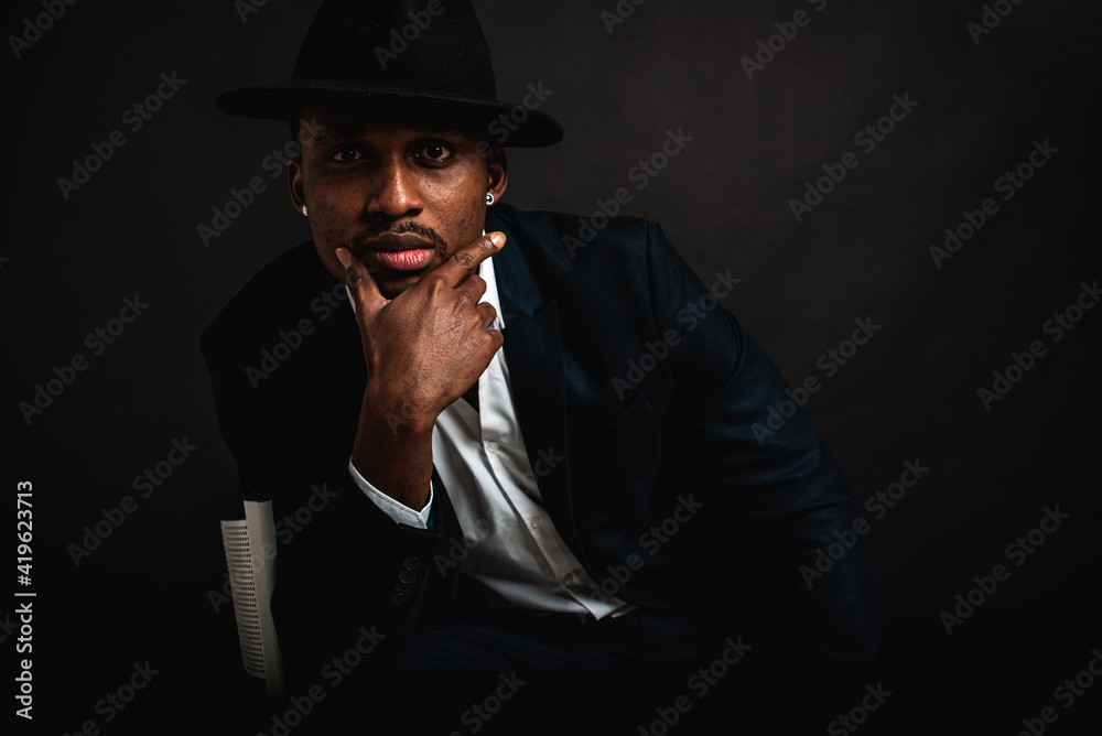 Portrait of attractive, handsome, stylish professional African American businessman in stylish suit and white shirt pensive holding hand near face, isolated on dark background. Low key. Selective focu Portrait of attractive, handsome, stylish professional African American businessman in stylish suit and white shirt pensive holding hand near face, isolated on dark background. Low key. Selective focu