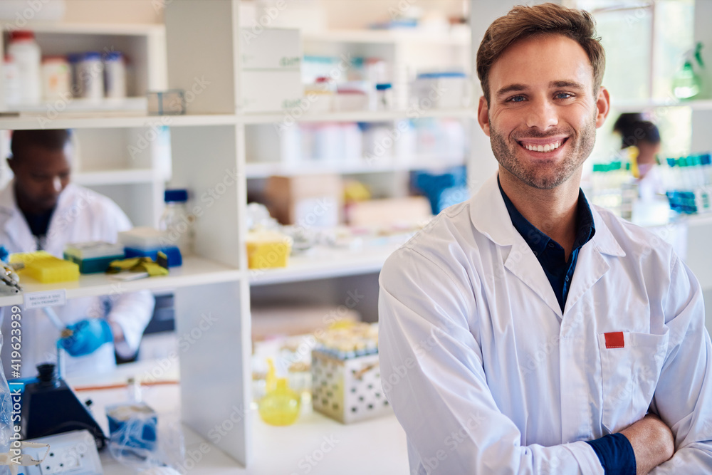 Smiling male technician working with colleagues in a lab