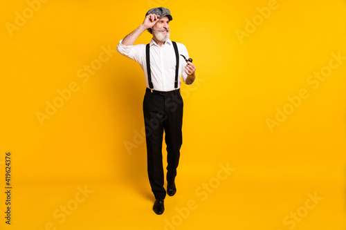Full length photo of mature man happy positive smile hold pipe smoker tobacco go walk isolated over yellow color background