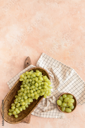 Basket with ripe green grapes on color background