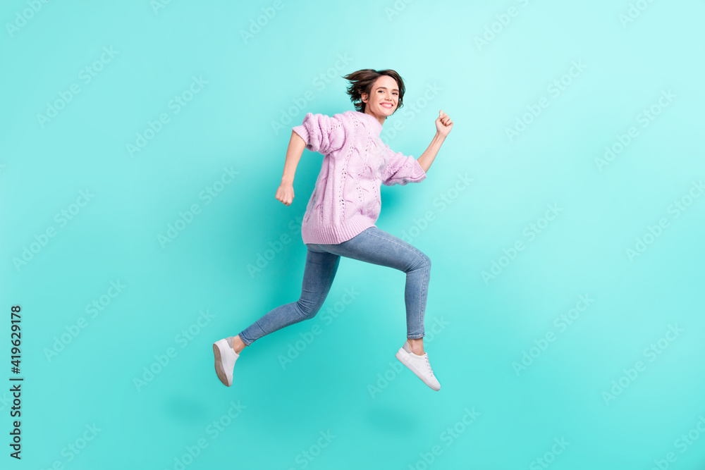 Full length photo of shiny cute young woman wear violet sweater running jumping isolated turquoise color background