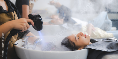 Hairdresser in beauty salon hair care in procedure of steaming water steam. Service steaming ozone in spa and salon shop, Woman having her hair washed in a hairdressing salon, massage head customer