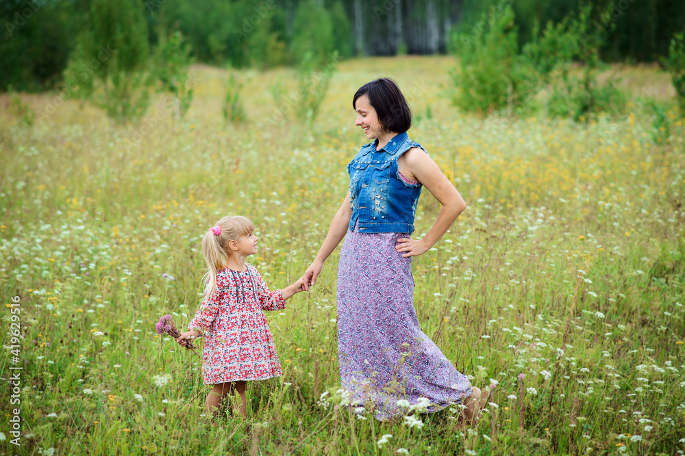 Smiling mother and daughter in the meadow enjoy a beautiful summer day Smiling mother and daughter in the meadow enjoy a beautiful summer day
