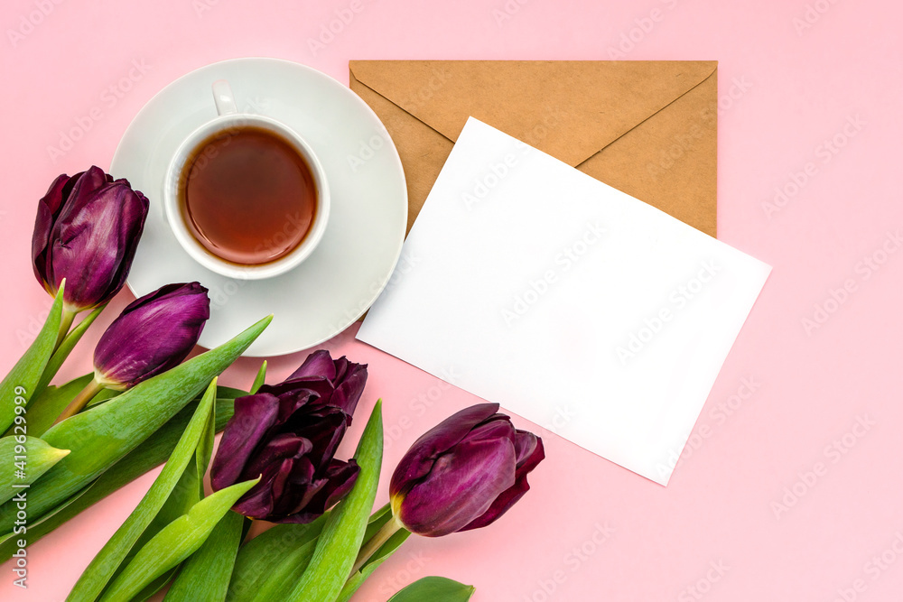 White paper and envelope for writing and tulip flowers on a pastel background, space for text White paper and envelope for writing and tulip flowers on a pastel background, space for text