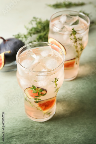 Glasses of tasty fig lemonade on grunge background