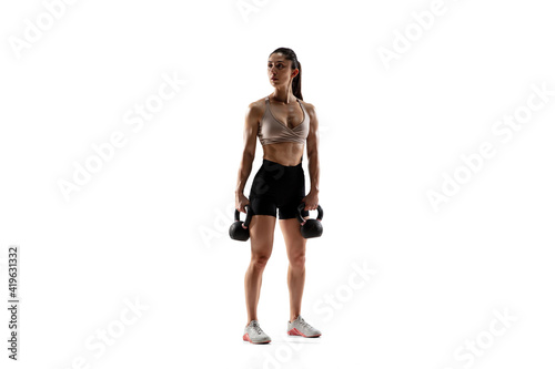Dumbbells. Caucasian professional female athlete training isolated on white studio background. Muscular, sportive woman. Concept of action, motion, youth, healthy lifestyle. Copyspace for ad.