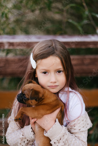 little girl with a hairpin in her hair holding a dog
