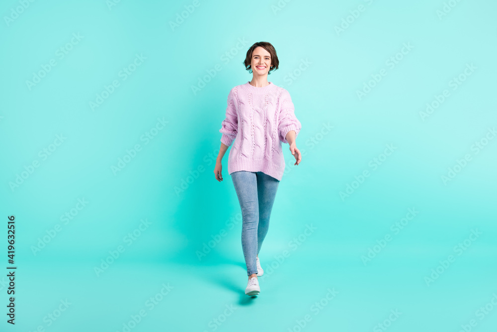 Full length photo of charming pretty young woman wear violet sweater walking isolated turquoise color background Full length photo of charming pretty young woman wear violet sweater walking isolated turquoise color background