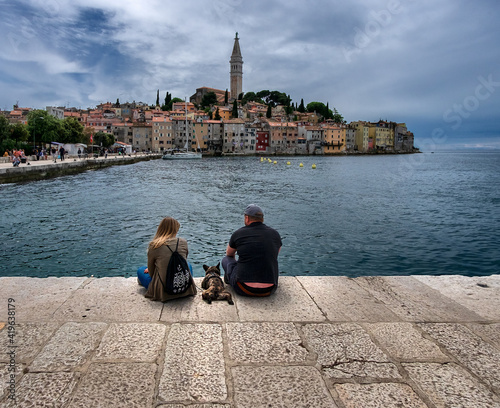Walking together with a dog on the waterfront of the old town of Rovinj. Resorts of Croatia.