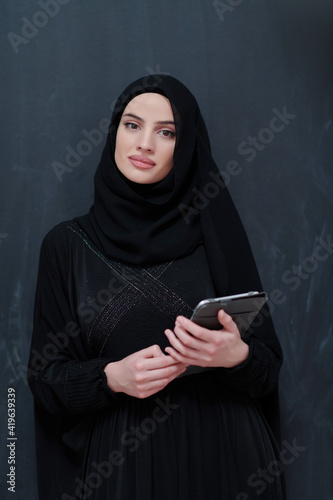 Young Arab businesswoman in traditional clothes or abaya with tablet computer