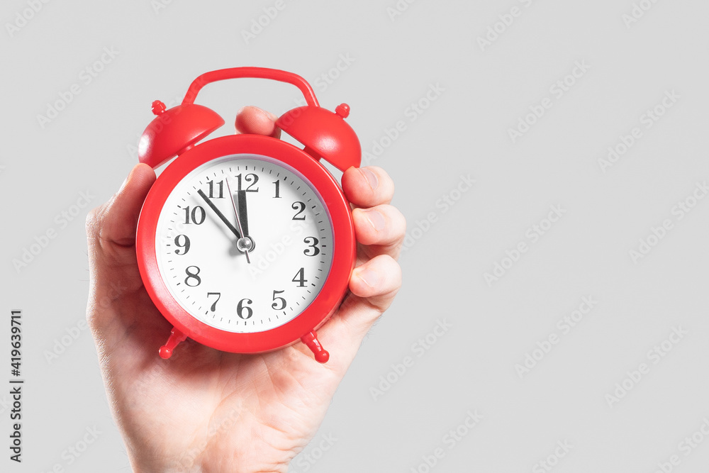 Analog red alarm clock in hand on a white background. Analog red alarm clock in hand on a white background.