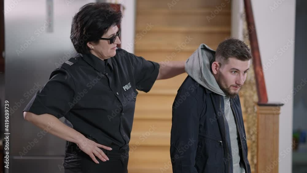 Scared young Caucasian thief grabbed by the collar. Strong confident