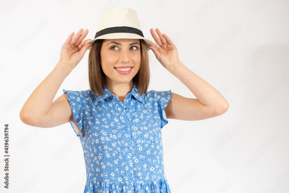 Beautiful young woman laughing woman in blue dress and straw hat looking happy over white background Beautiful young woman laughing woman in blue dress and straw hat looking happy over white background