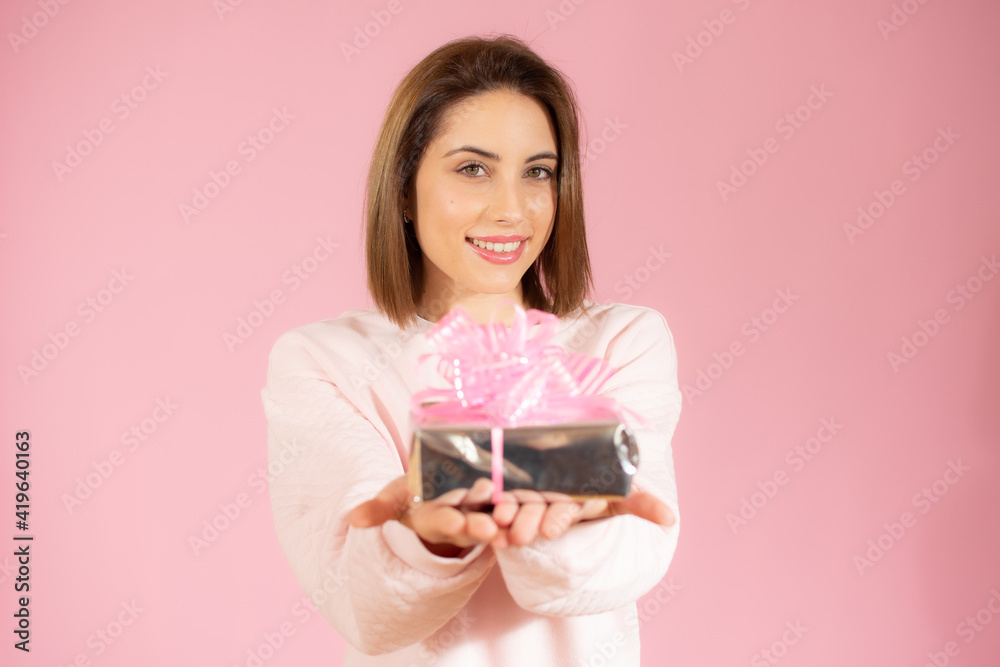 Happy smiling woman showing small gift box isolated over pink background. Happy smiling woman showing small gift box isolated over pink background.