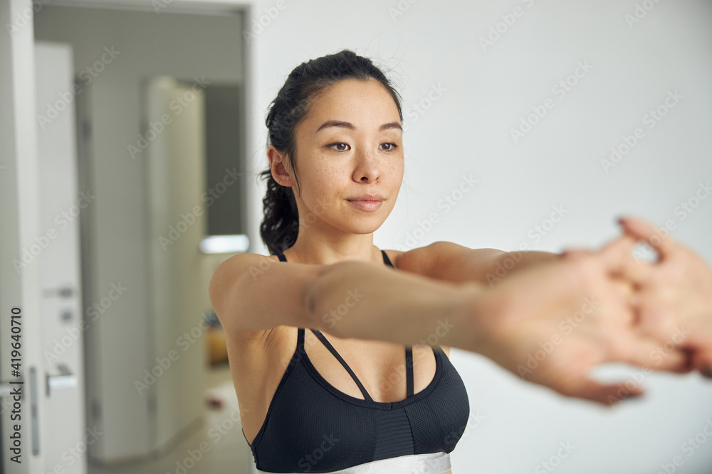 Happy beautiful asian woman is doing morning sport exercises at cozy bedroom