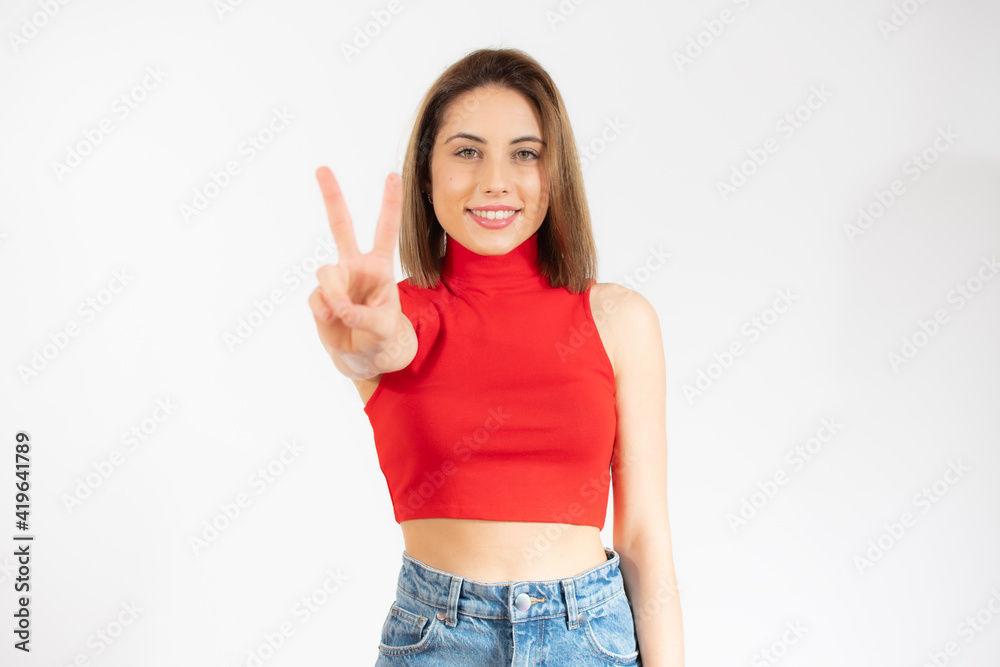 Young pretty woman isolated showing victory sign and smiling broadly. Young pretty woman isolated showing victory sign and smiling broadly.