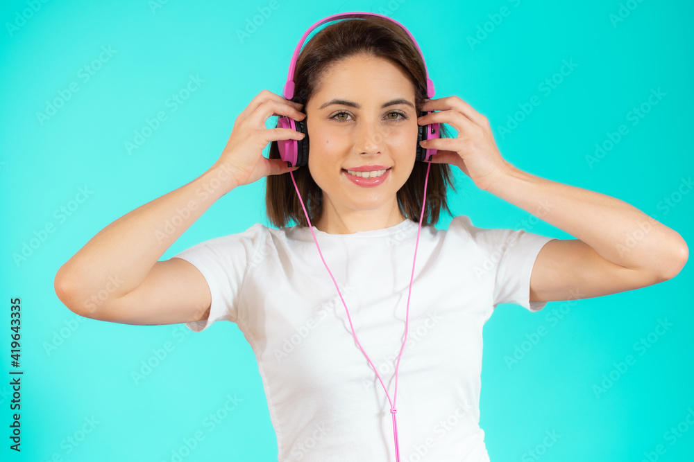 Photo of happy positive optimistic young woman posing isolated over green background listening music with headphones. Photo of happy positive optimistic young woman posing isolated over green background listening music with headphones.