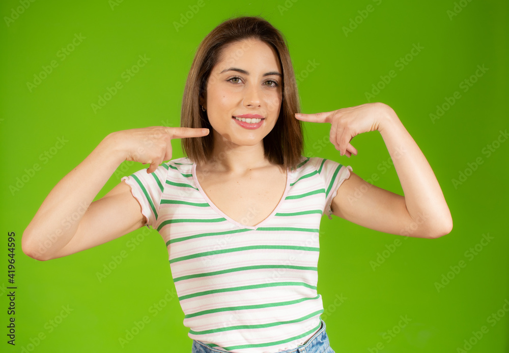 Beautiful young woman pointing to teeth over green background. Beautiful young woman pointing to teeth over green background.