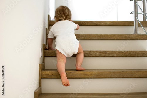 Wallpaper Mural Little caucasian baby is crawling on stairs at home in sunny interior. Lifestile photography. Child safety at home and barefoot concept. Torontodigital.ca