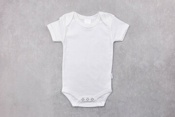 White baby girl or boy bodysuit mockup on the gray concrete background. Design onesie template, print presentation mock up. Top view. Flat Lay.