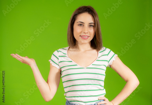 Happy woman presenting with open hand holding something blank isolated over green background