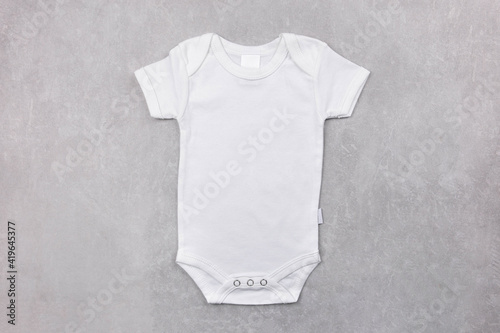 White baby girl or boy bodysuit mockup on the gray concrete background. Design onesie template, print presentation mock up. Top view. Flat Lay.