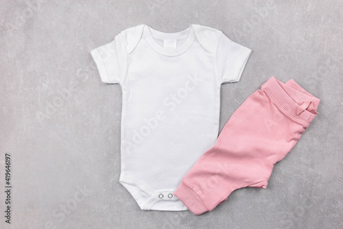 White baby girl bodysuit mockup on the gray concrete background with pink panties. Design onesie template, print presentation mock up. Top view. Flat Lay. © AnaWein
