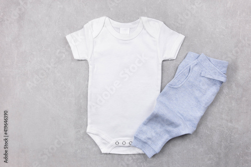 White baby girl or boy bodysuit mockup on the gray concrete background with blue panties. Design onesie template, print presentation mock up. Top view. Flat Lay. © AnaWein