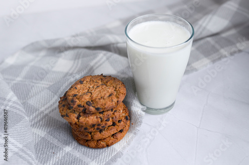 A glass of milk and a stack of homemade oatmeal cookies on a light white background. The concept of proper nutrition. Breakfast in the village. copy space for text. top view