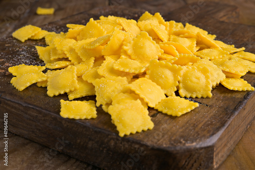 Tartollini with cheese or meat for cooking in broth, Traditional dish for celebrations in italy, Emilia Romagna region. Fresh homemade pasta with filling on a wooden table.