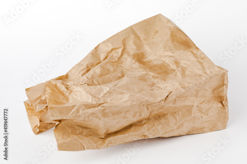 Crumpled paper bag with greasy spots on a white isolated background. Recycling of secondary waste