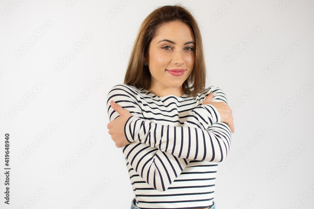 Portrait of a pretty young woman in striped t-shirt hugging herself. Concept of selfish emotion. Portrait of a pretty young woman in striped t-shirt hugging herself. Concept of selfish emotion.