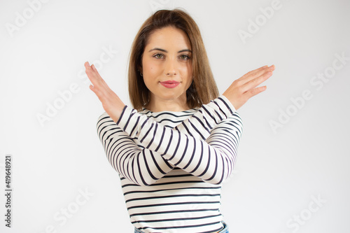 Young woman wearing striped t-shirt with rejection expression crossing arms and palms doing negative sign.