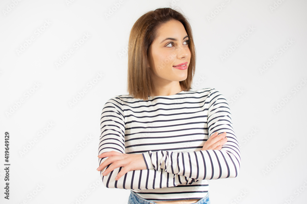 Portrait of a smiling young woman standing with arms folded and looking away at copy space isolated over white background Portrait of a smiling young woman standing with arms folded and looking away at copy space isolated over white background