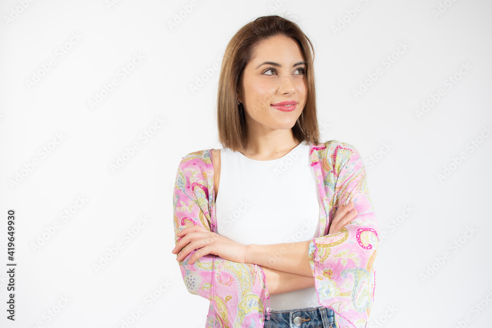 Portrait of a smiling young woman standing with arms folded and looking away at copy space isolated over white background Portrait of a smiling young woman standing with arms folded and looking away at copy space isolated over white background