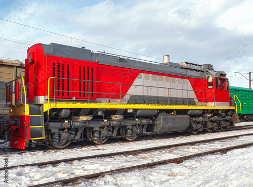 Switcher with train of freight cars in line at a rail yard. Small desel manoeuvring locomotive.